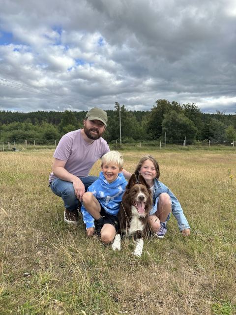 David crouched in a field with his two young children and their dog
